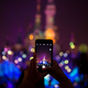 A tourist takes a photo with an iPhone at Shanghai Disneyland